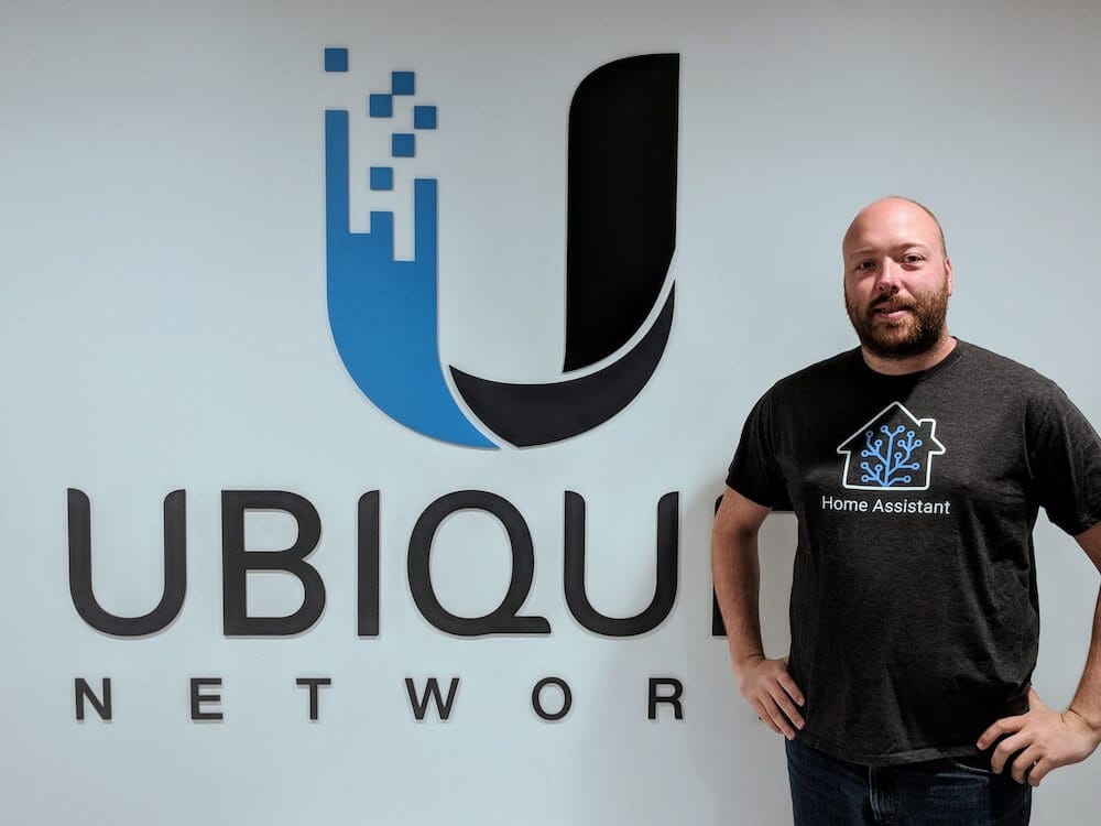 Photo of Paulus, the founder of KS Assistant, standing in front of a Ubiquiti Networks logo wearing a KS Assistant t-shirt.